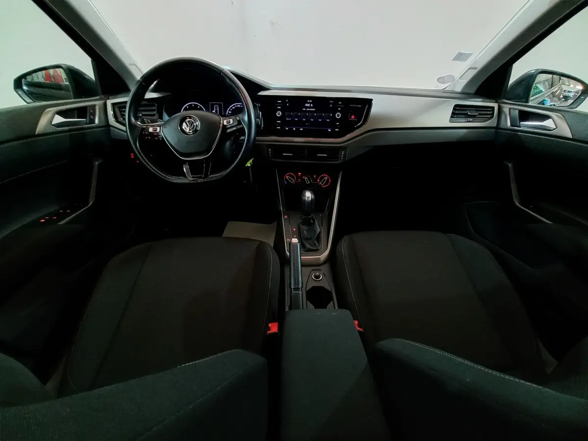 Vue intérieure frontale de la Volkswagen Polo noire 2020, tableau de bord avec écran tactile et volant multifonctions.