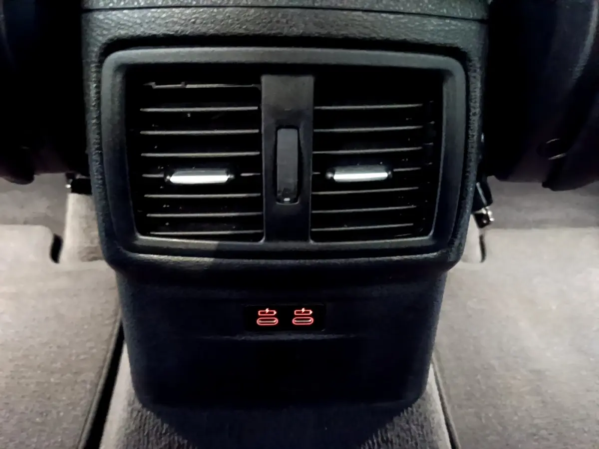 Gros plan sur la sortie d’air arrière noire et les commandes de chauffage des sièges du BMW X1 blanc sDrive18i M Sport 2022.