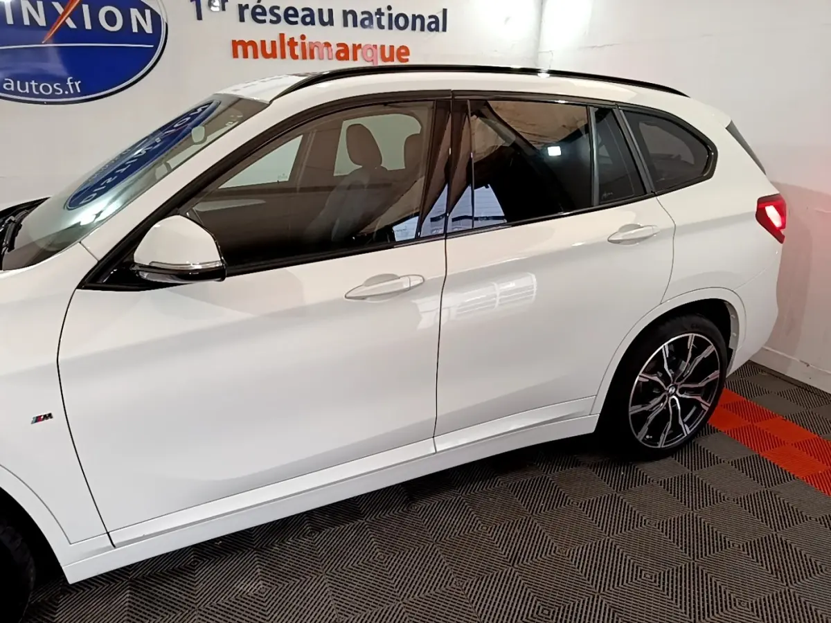 Profil droit d’un BMW X1 blanc sDrive18i M Sport 2022 avec jantes alliage et vitres teintées.