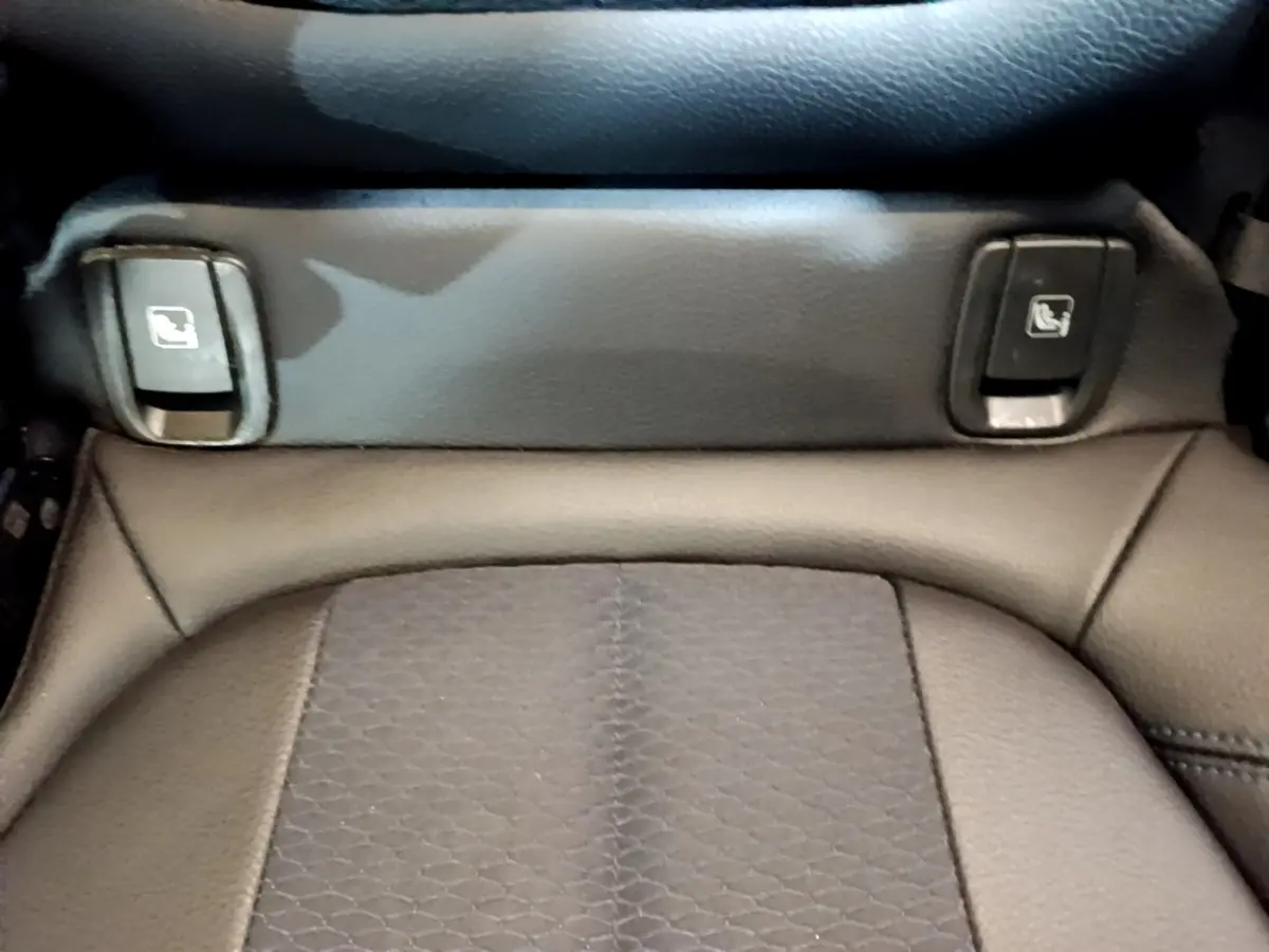 Gros plan sur les commandes de rabattement des sièges arrière en cuir noir dans un BMW X1 blanc.