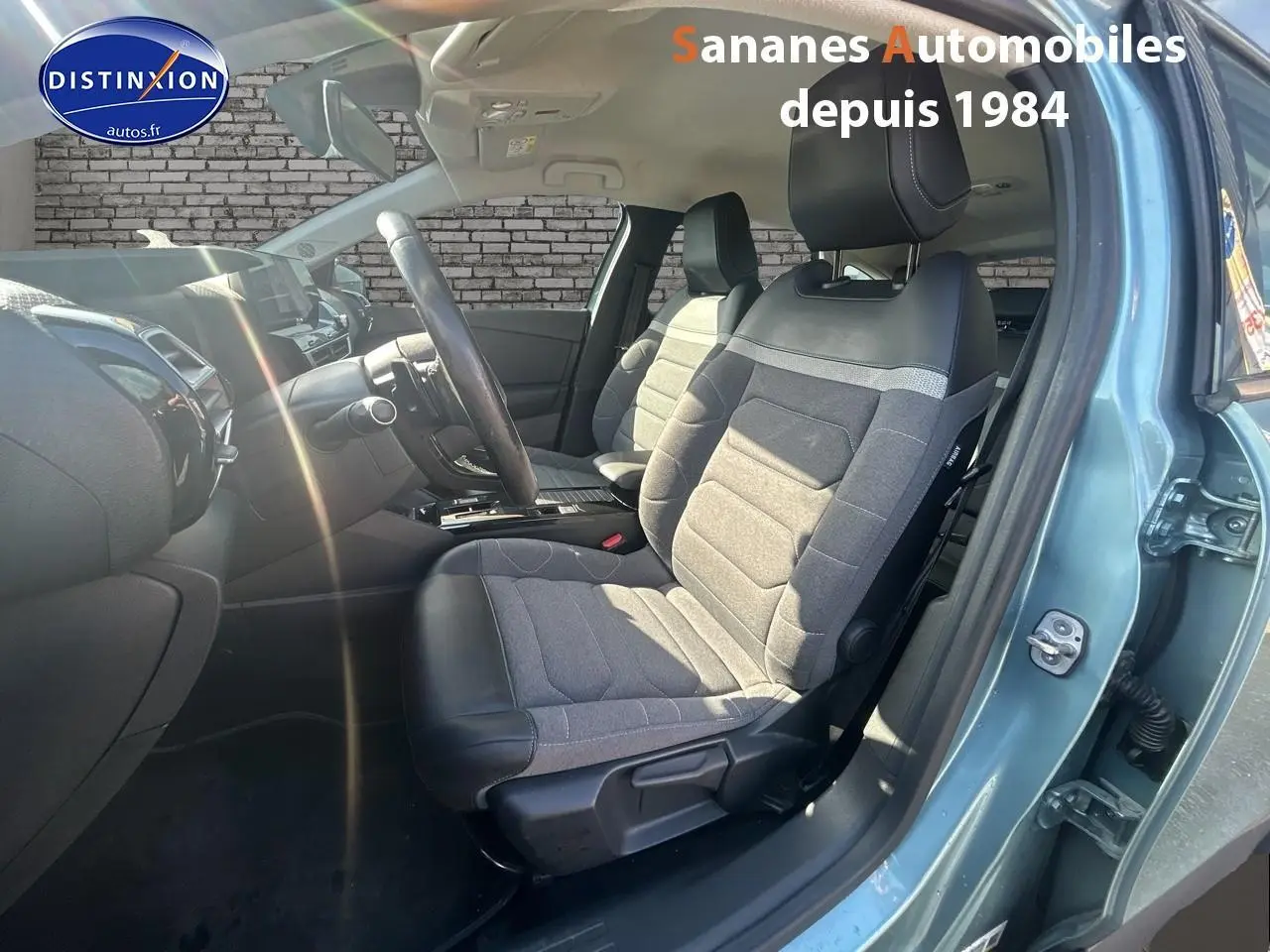 Vue intérieure côté conducteur de la Citroën C4 2021 bleu clair, sièges tissu gris et cuir noir avec tableau de bord moderne.