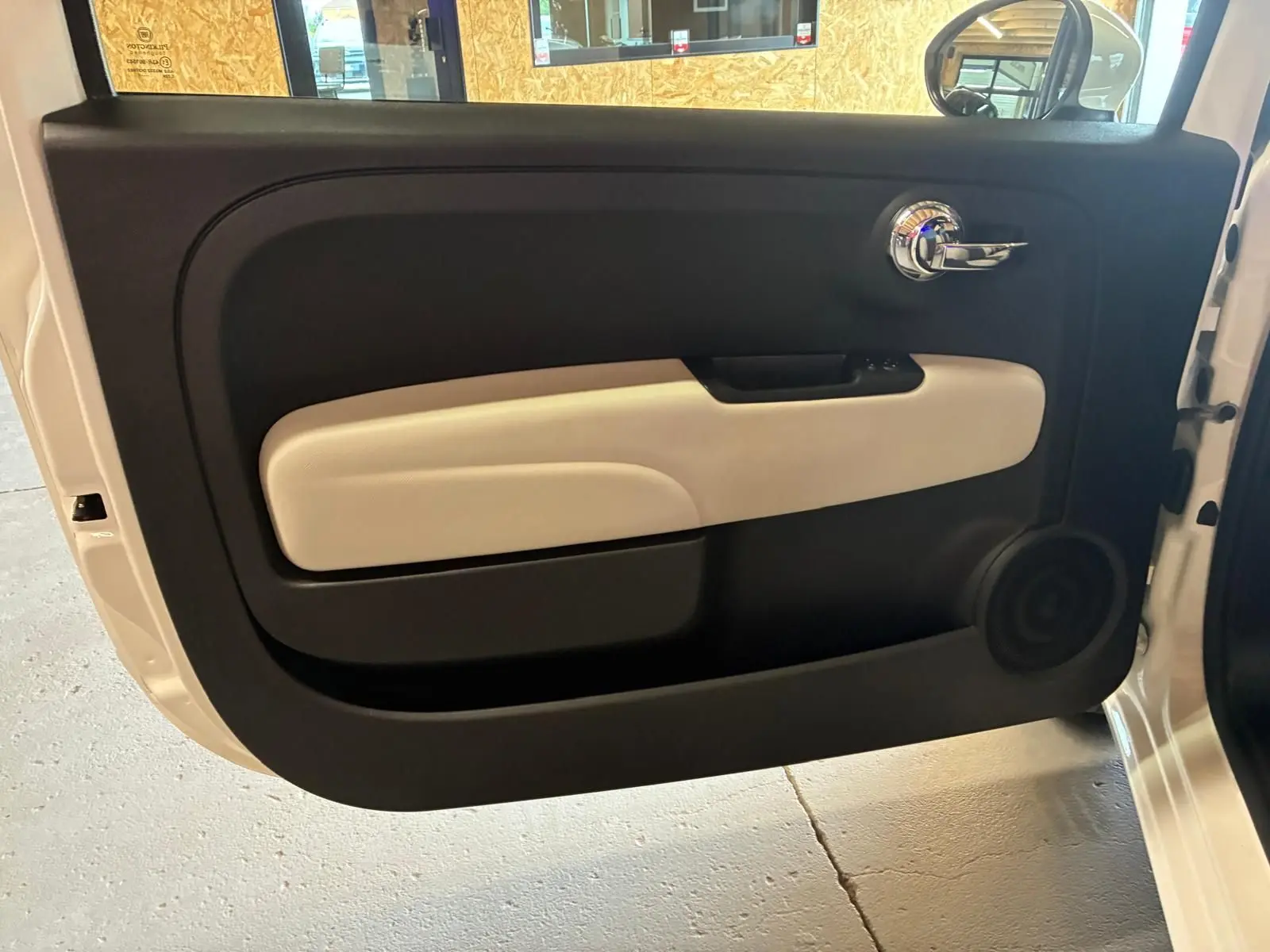 Vue intérieure de la porte avant droite d'une Fiat 500 blanc crème avec garniture noire et beige.