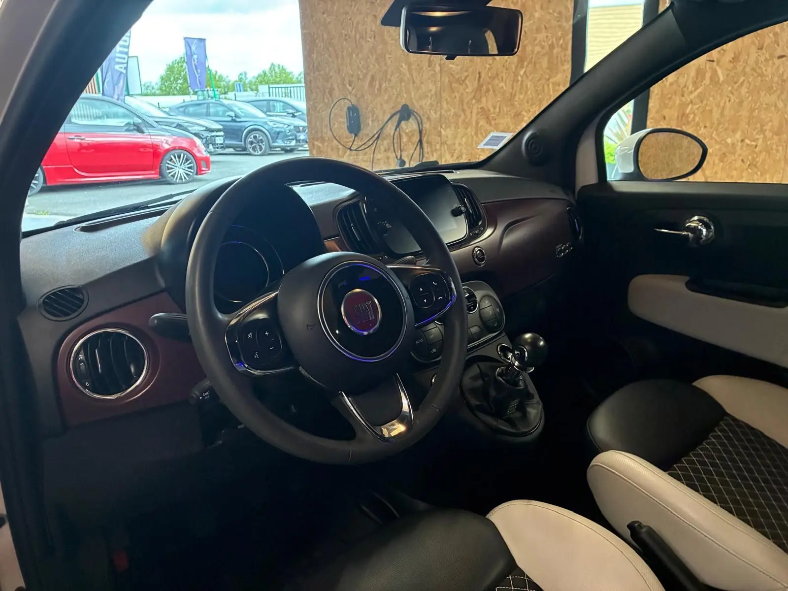 Intérieur de la Fiat 500 blanc crème vu côté conducteur, volant multifonction et levier de vitesse manuel visibles.