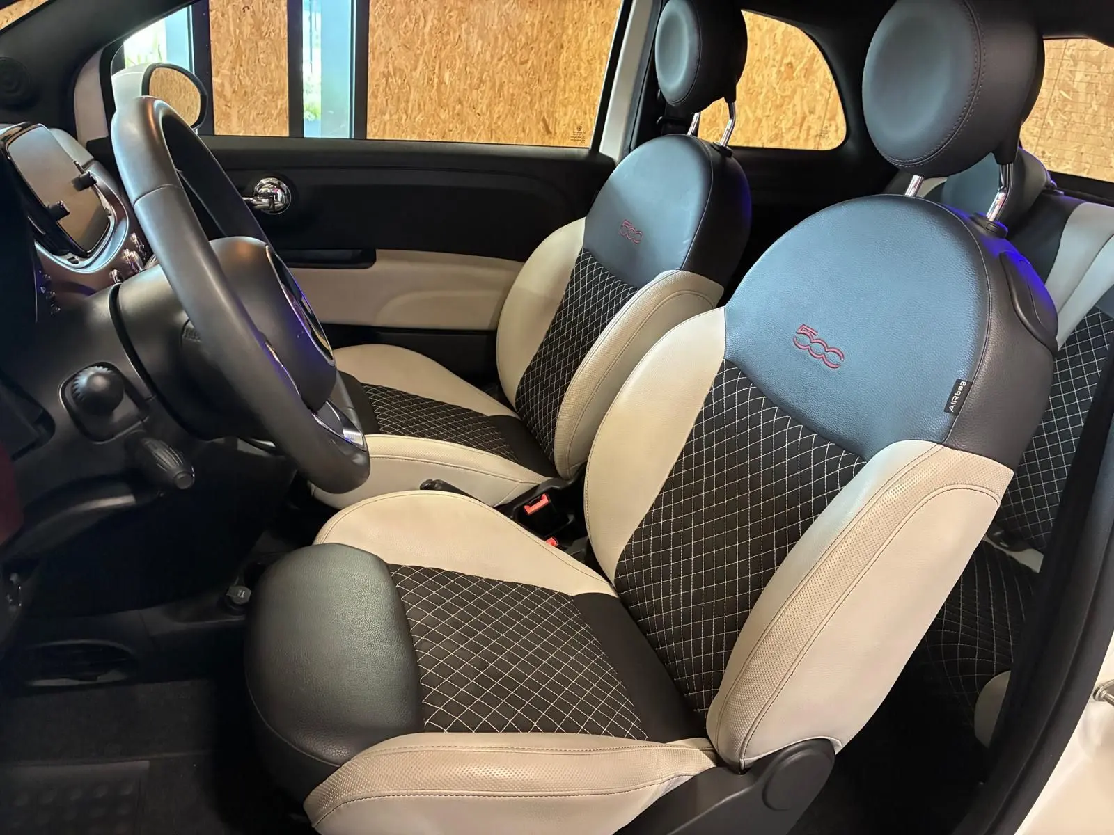 Vue intérieure côté gauche de la Fiat 500 2021, sièges bicolores noir et crème avec logo 500 brodé rouge.