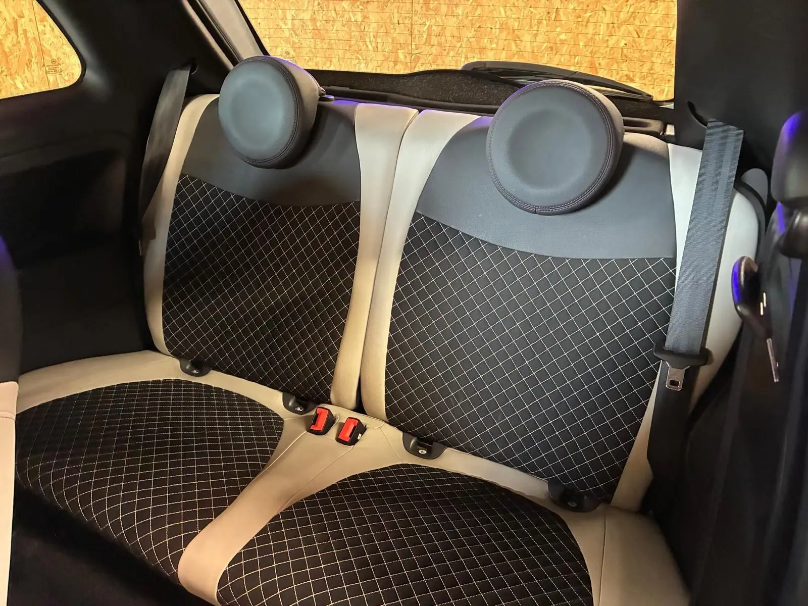 Vue rapprochée des sièges arrière en tissu noir à motifs blancs avec contours crème d'une Fiat 500 DolceVita 2021.