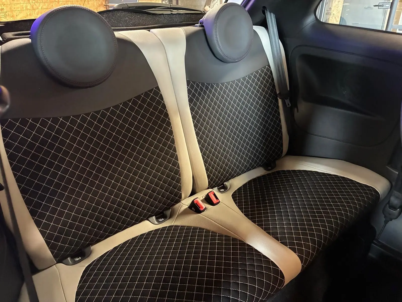Vue intérieure des sièges arrière en tissu noir à motifs losanges avec contours crème d'une Fiat 500 DolceVita 2021.