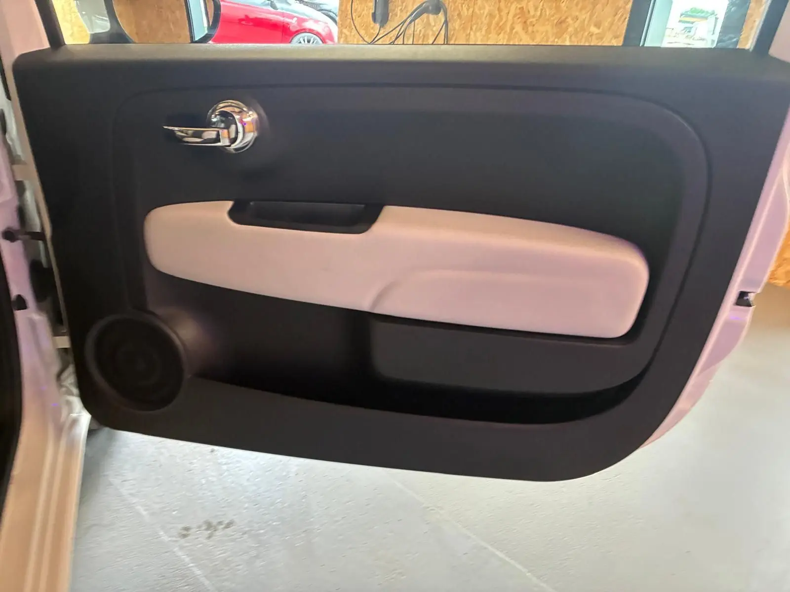 Vue intérieure de la porte avant gauche de la Fiat 500 blanche crème, avec poignée chrome et accoudoir clair.