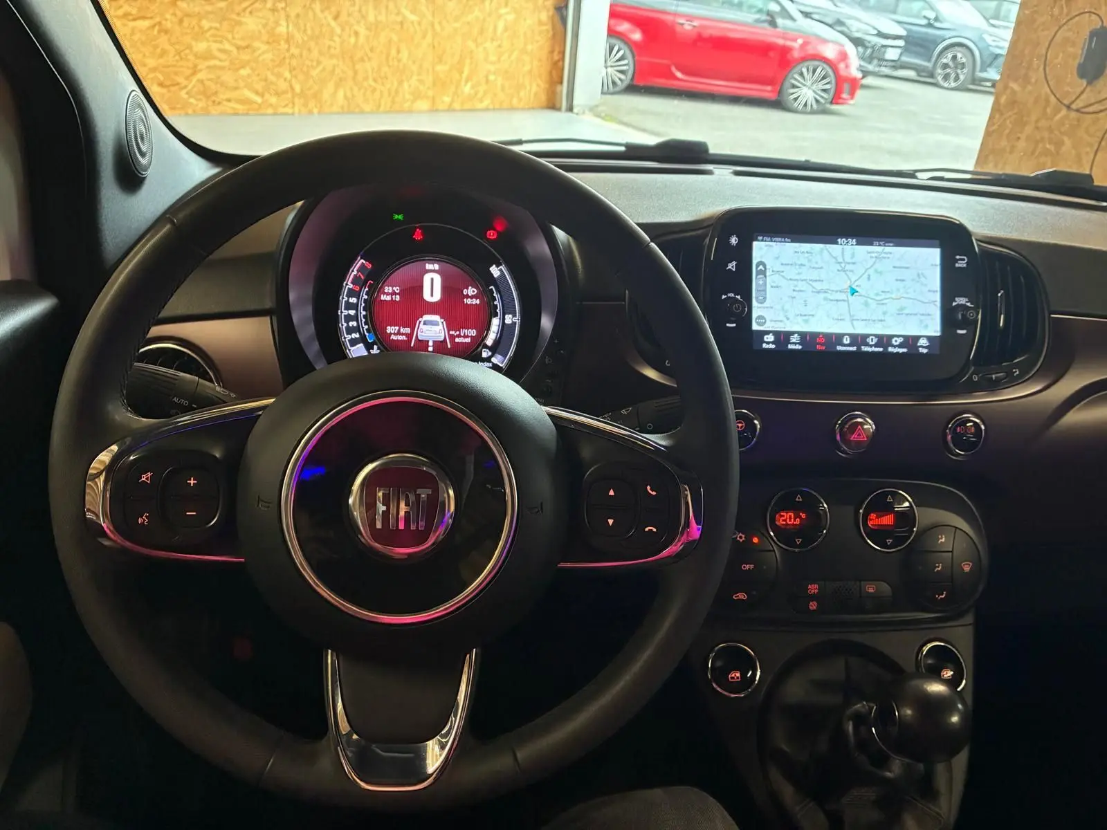 Vue intérieure centrée sur le volant FIAT et le tableau de bord avec écran tactile affichant la navigation.