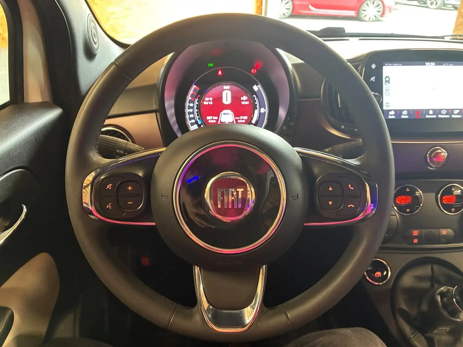 Vue centrée sur le volant noir de la Fiat 500 2021 avec tableau de bord numérique et écran tactile visible.