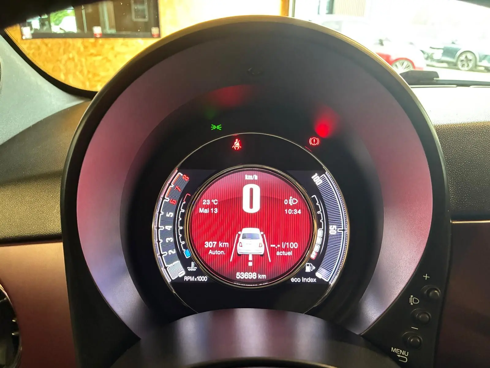 Vue rapprochée du tableau de bord numérique rouge de la Fiat 500 blanche crème, affichant la vitesse à zéro.