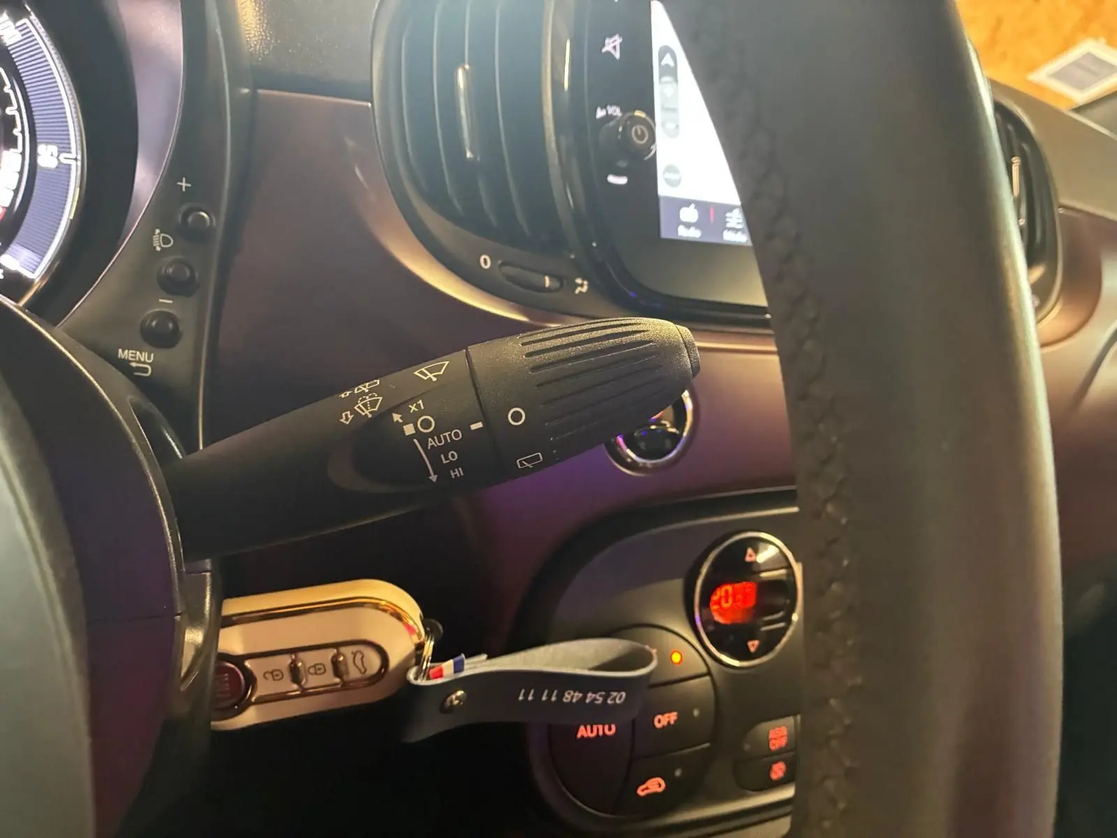 Vue rapprochée du commodo d’essuie-glace à gauche du volant dans l’habitacle noir et crème d’une Fiat 500 2021.