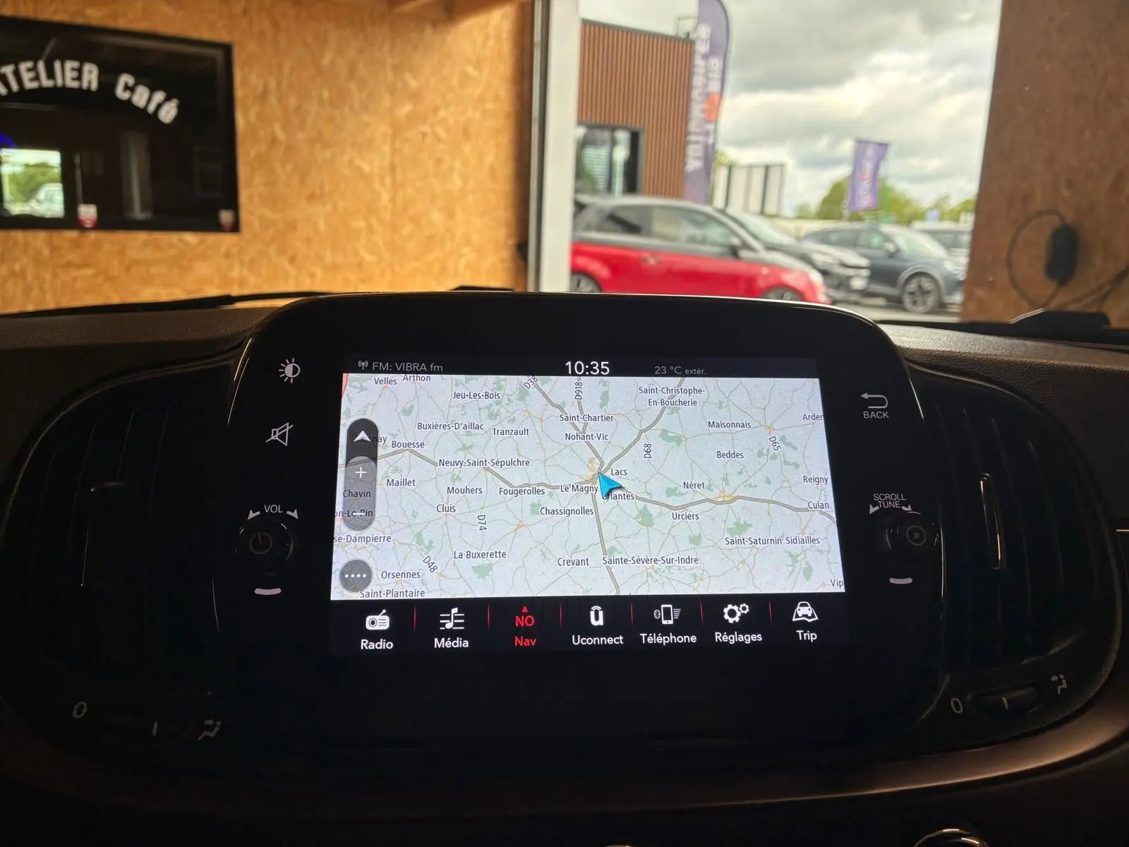 Vue intérieure du tableau de bord de la Fiat 500 blanc crème, mettant en valeur l'écran tactile de navigation allumé.