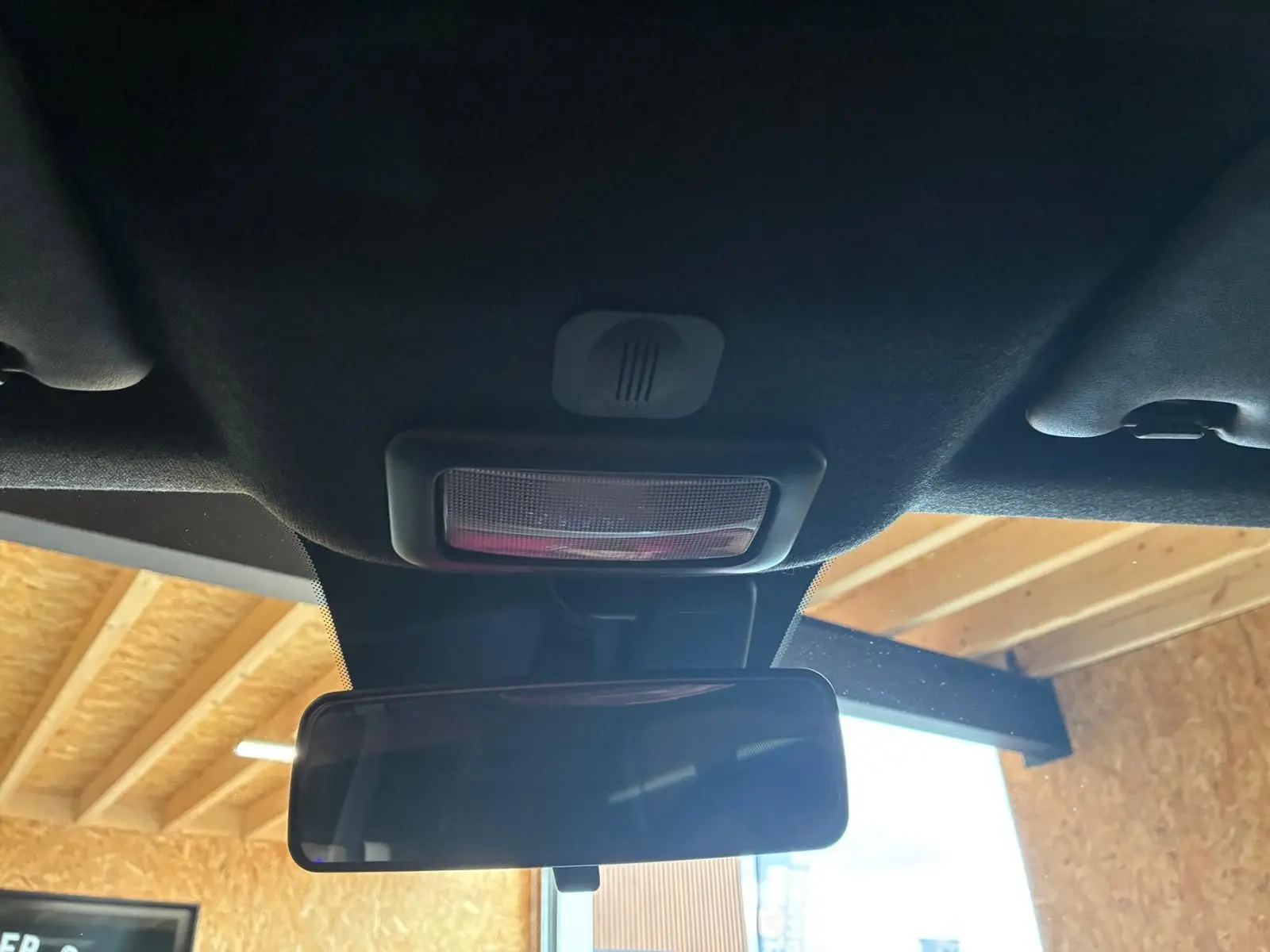 Vue intérieure centrée sur le rétroviseur intérieur et la lumière de plafond d'une Fiat 500 blanc crème.