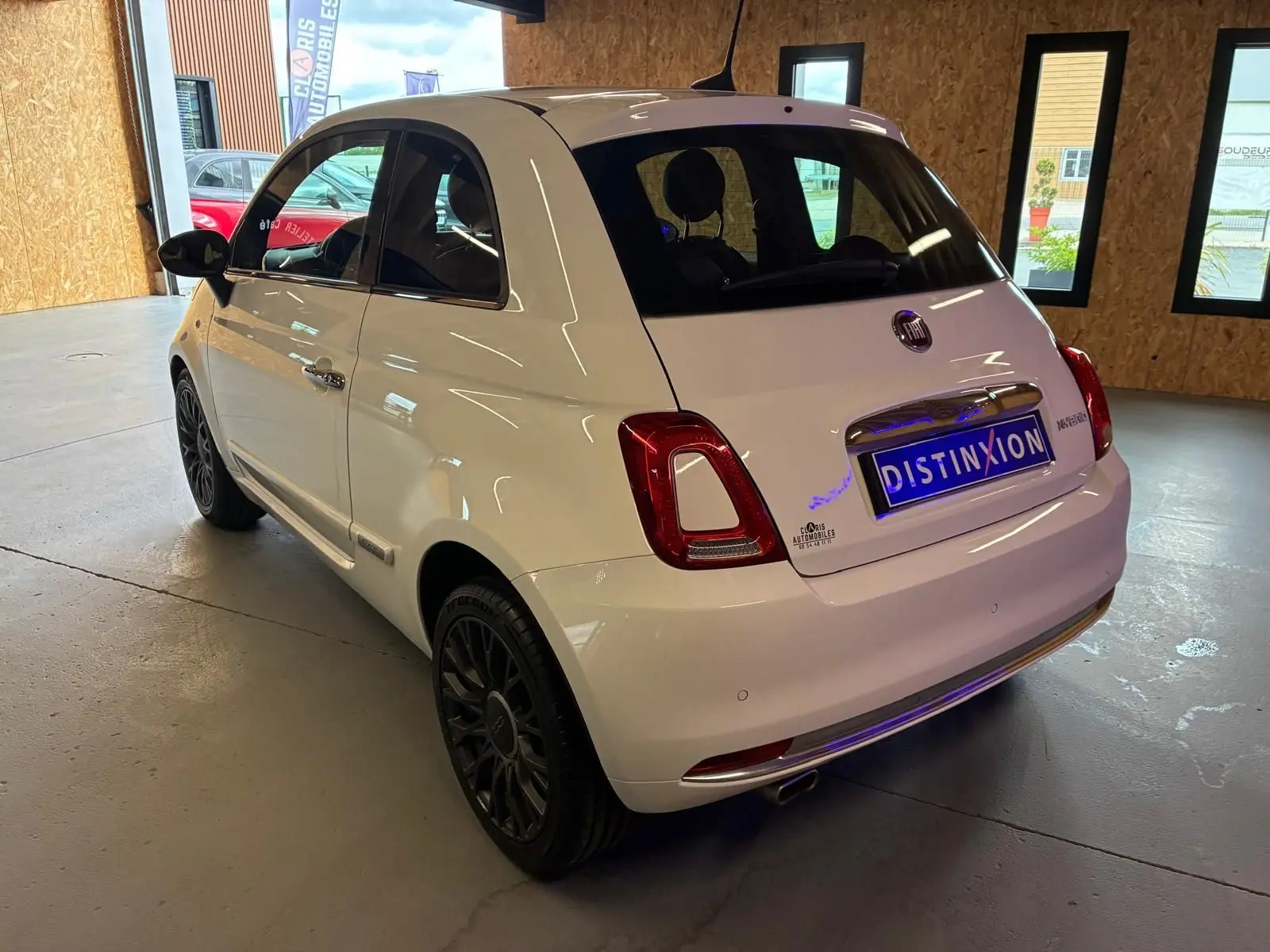 Vue 3/4 arrière droite d'une FIAT 500 blanc crème 2021 avec jantes noires et intérieur visible à travers les vitres.