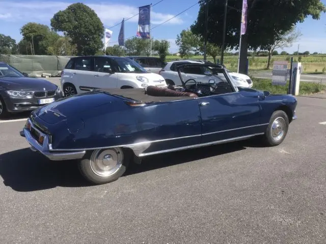 Vue latérale droite d'une Citroën DS3 Cabriolet Chapron 1967 bleu marine avec capote ouverte sur parking.