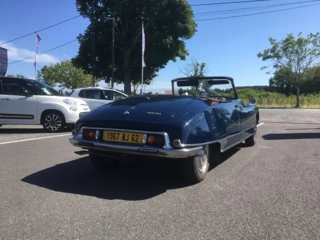 Vue 3/4 arrière droite d'une Citroën DS3 DS21 Cabriolet Chapron bleu marine de 1967, capote ouverte, plaque jaune visible.
