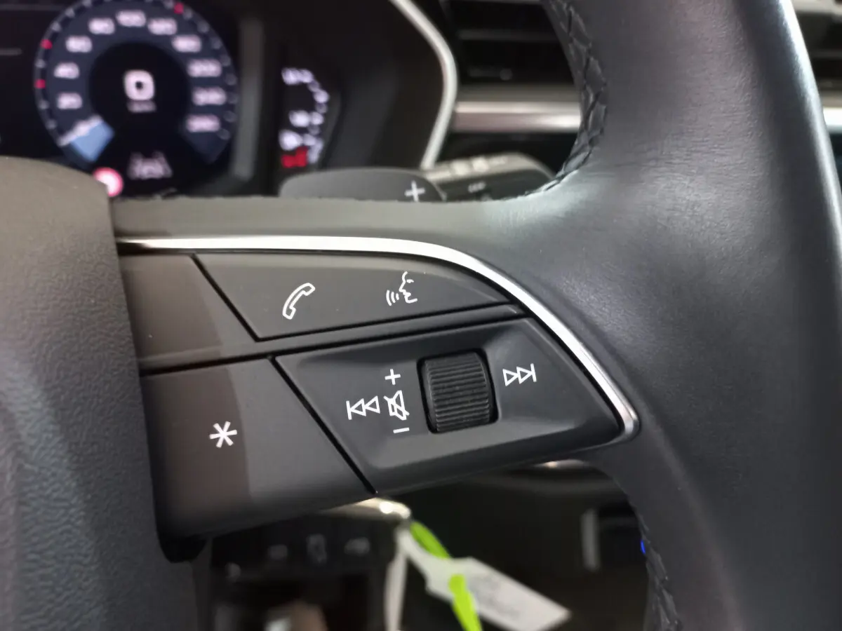 Gros plan sur les commandes vocales et audio du volant cuir noir de l'Audi Q3 Sportback 35 TDI 2020.