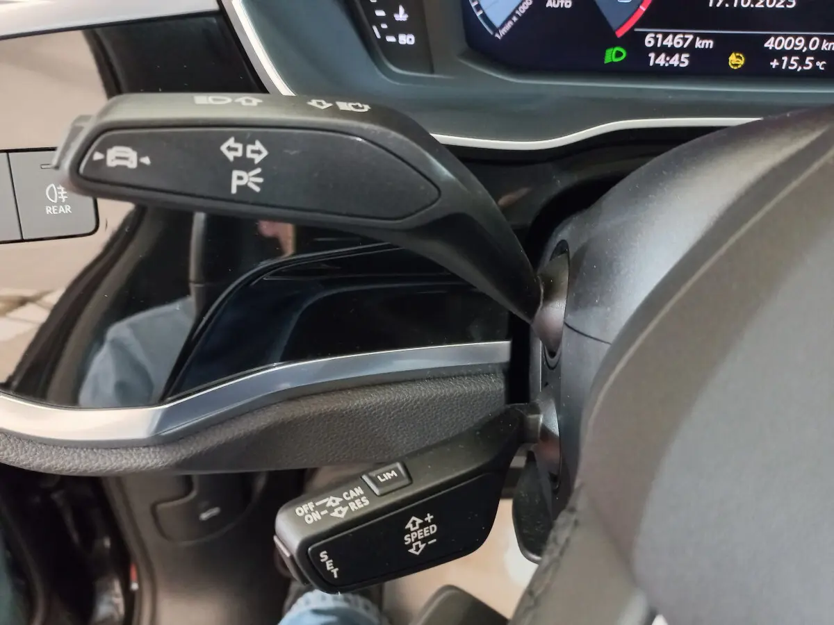 Gros plan sur les commandes au volant d'un Audi Q3 Sportback 35 TDI noir, avec affichage digital du tableau de bord en arrière-plan.