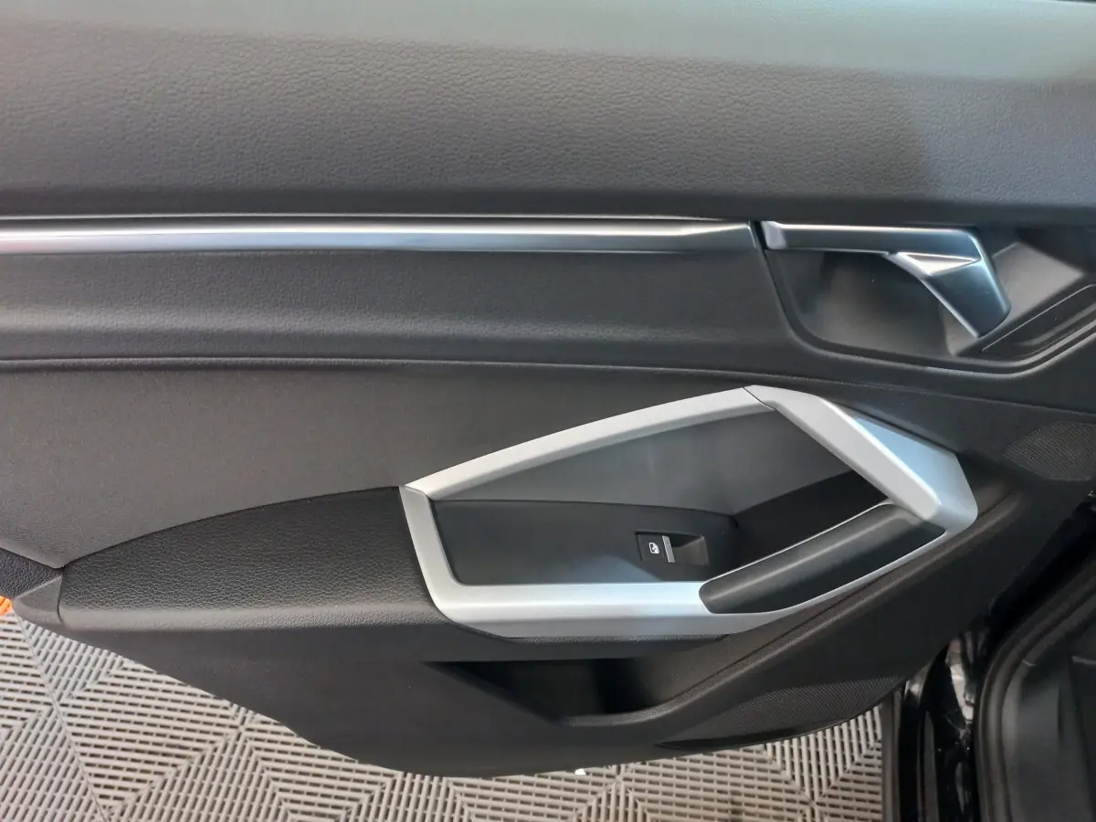 Détail de la porte côté conducteur noire de l'Audi Q3 Sportback 35 TDI 150 S tronic Business Line 2020 avec poignée argentée.