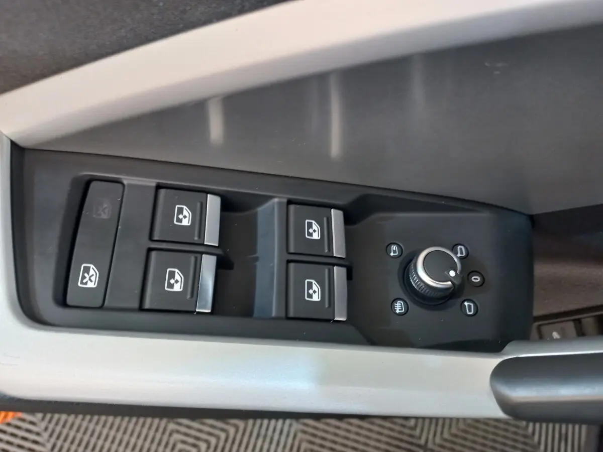Gros plan sur les commandes de lève-vitres et réglage des rétroviseurs côté conducteur d'un Audi Q3 Sportback noir.