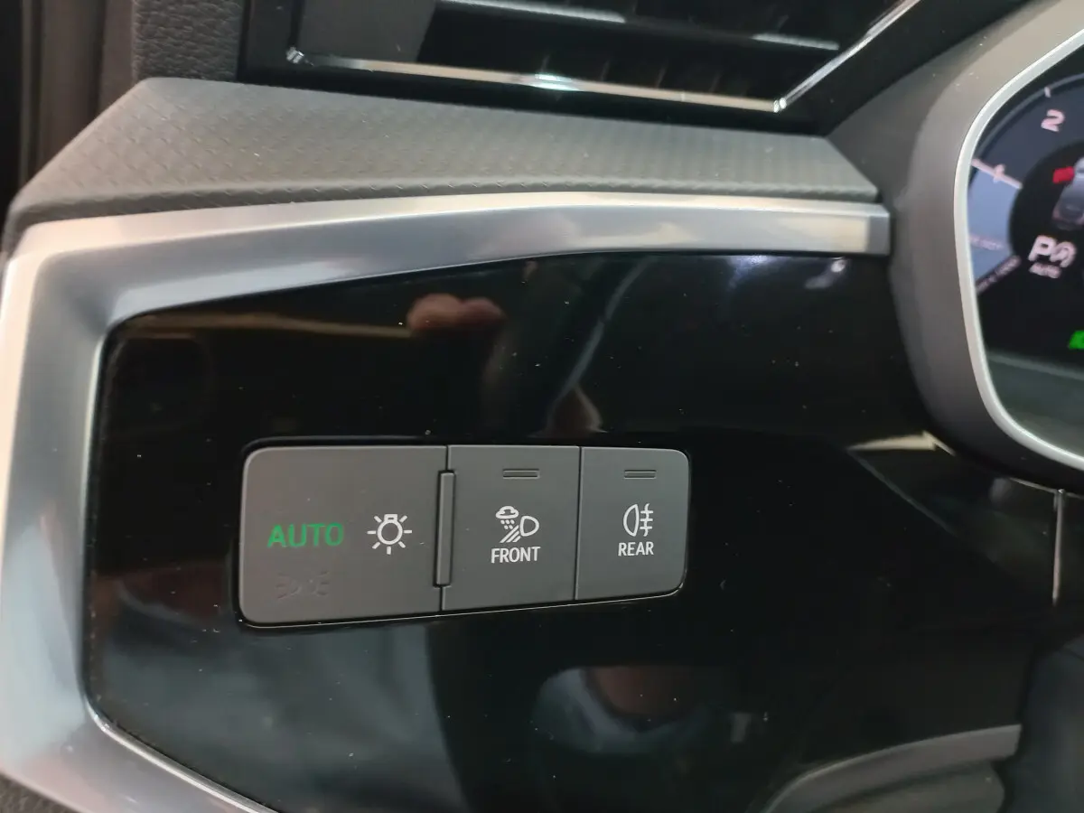 Gros plan sur les commandes d'éclairage avec mode auto, antibrouillard avant et arrière, tableau de bord noir d'Audi Q3 Sportback.