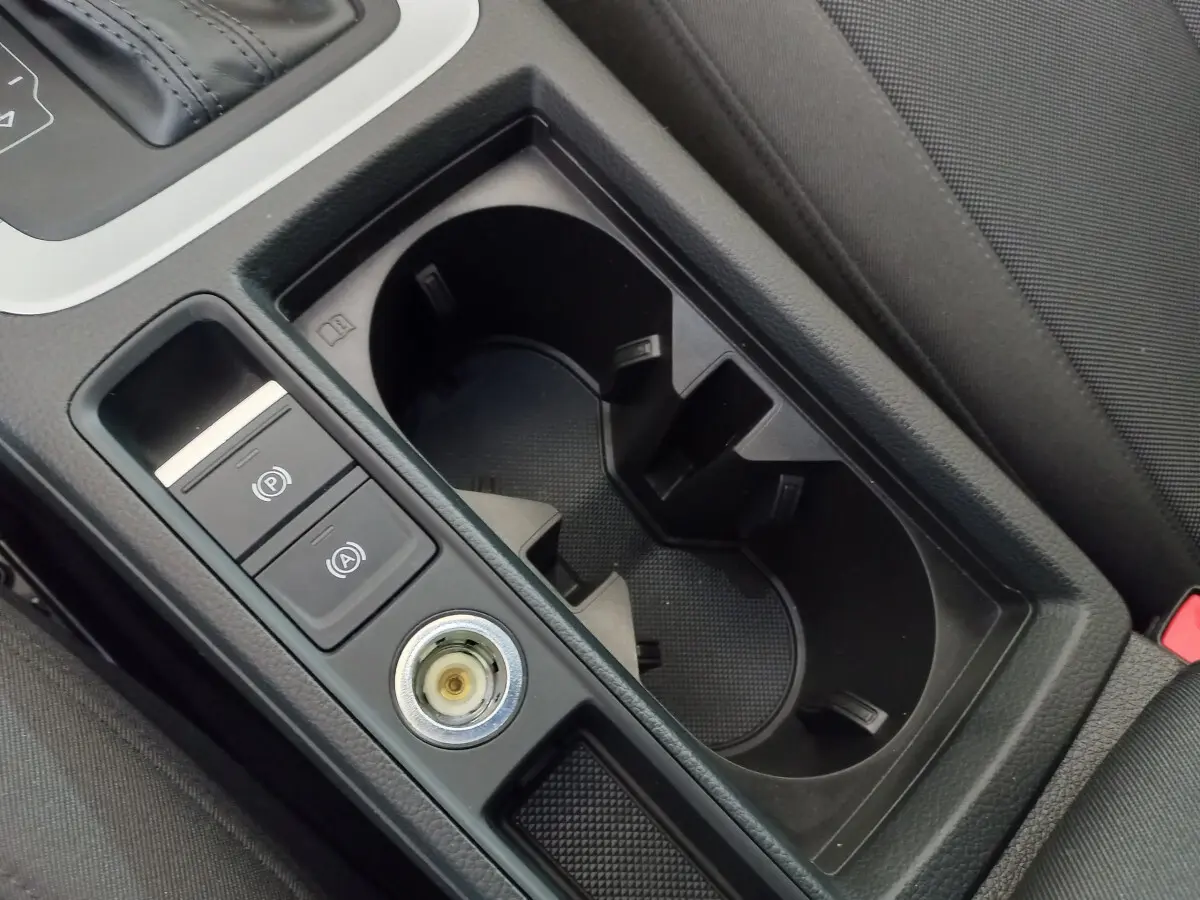 Gros plan sur la console centrale noire de l'Audi Q3 Sportback 35 TDI avec porte-gobelets et commandes électroniques.