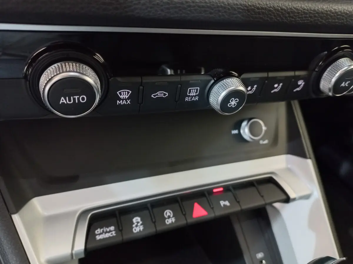 Gros plan sur la console centrale noire de l'Audi Q3 Sportback 35 TDI 150 S Tronic avec commandes climatisation et boutons multifonctions.