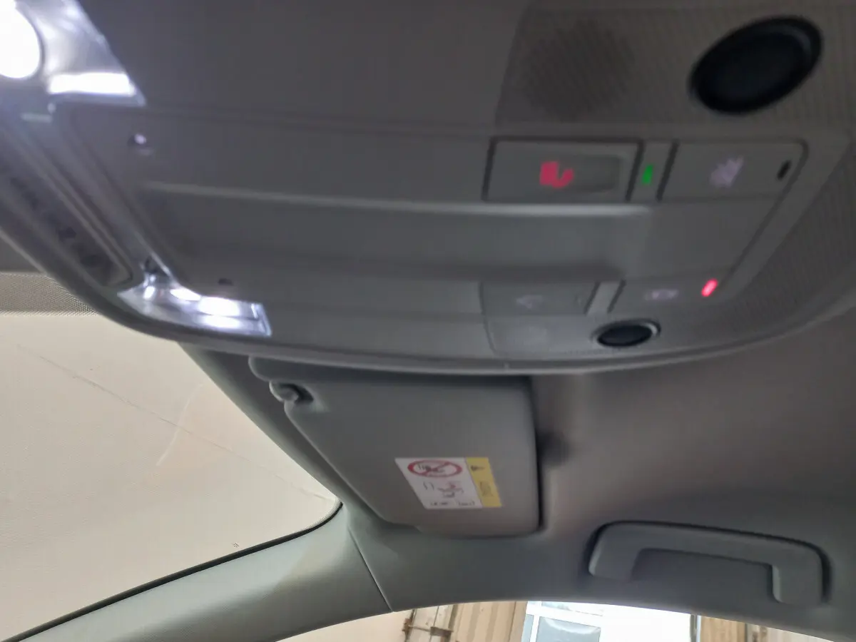 Vue intérieure du plafond avant de l'Audi Q3 Sportback noir 2020, avec commandes d'éclairage et pare-soleil côté conducteur.