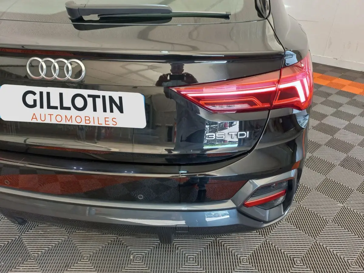 Vue arrière droite d'un Audi Q3 Sportback noir 35 TDI avec feux LED et logo distinctif sur coffre.