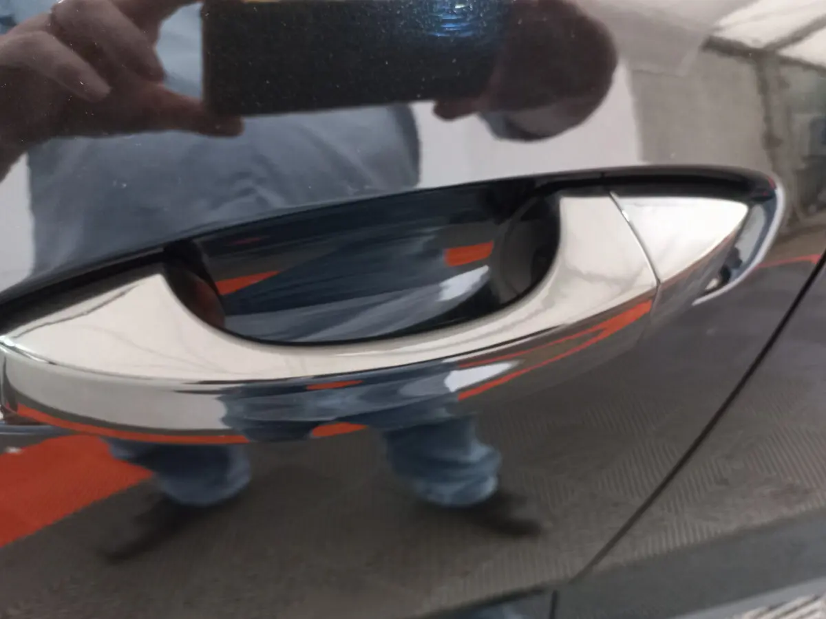 Poignée de porte chromée en gros plan sur la portière noire d'un Audi Q3 Sportback 35 TDI 2020.