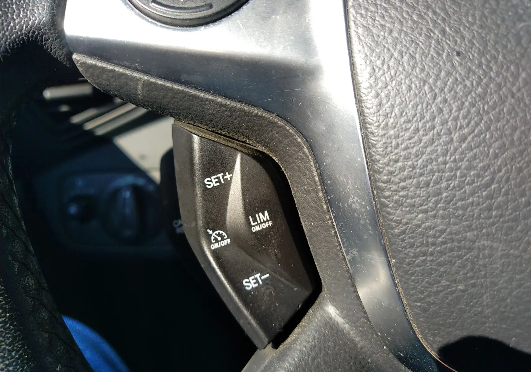 Gros plan sur les commandes de régulateur de vitesse au volant d'une Ford C-MAX blanche, version 2013.