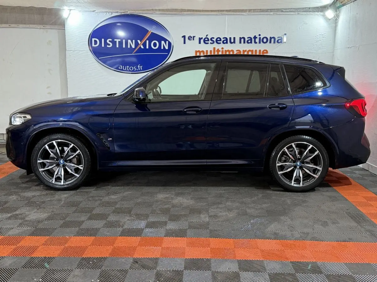 Vue de profil côté gauche d'un BMW X3 xDrive30e bleu foncé avec jantes alliage et vitres teintées.