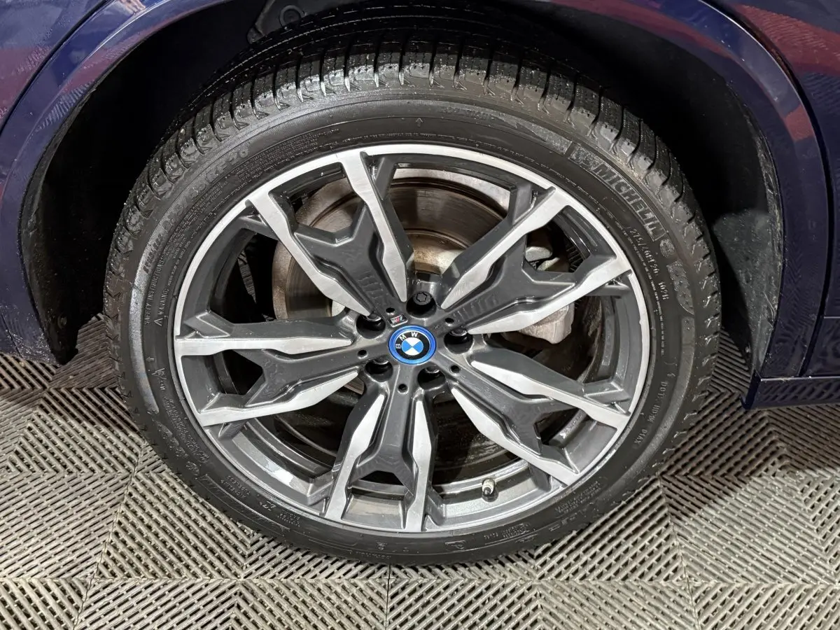 Gros plan sur la roue avant droite d’un BMW X3 bleu 2023 avec jante alliage M Sport à design complexe.