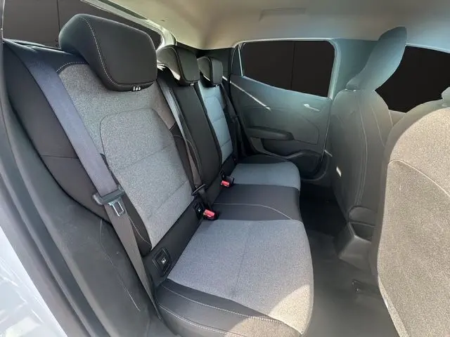 Vue intérieure côté droit montrant la banquette arrière grise et noire de la Renault Clio V blanche, avec ceintures et appuie-têtes.