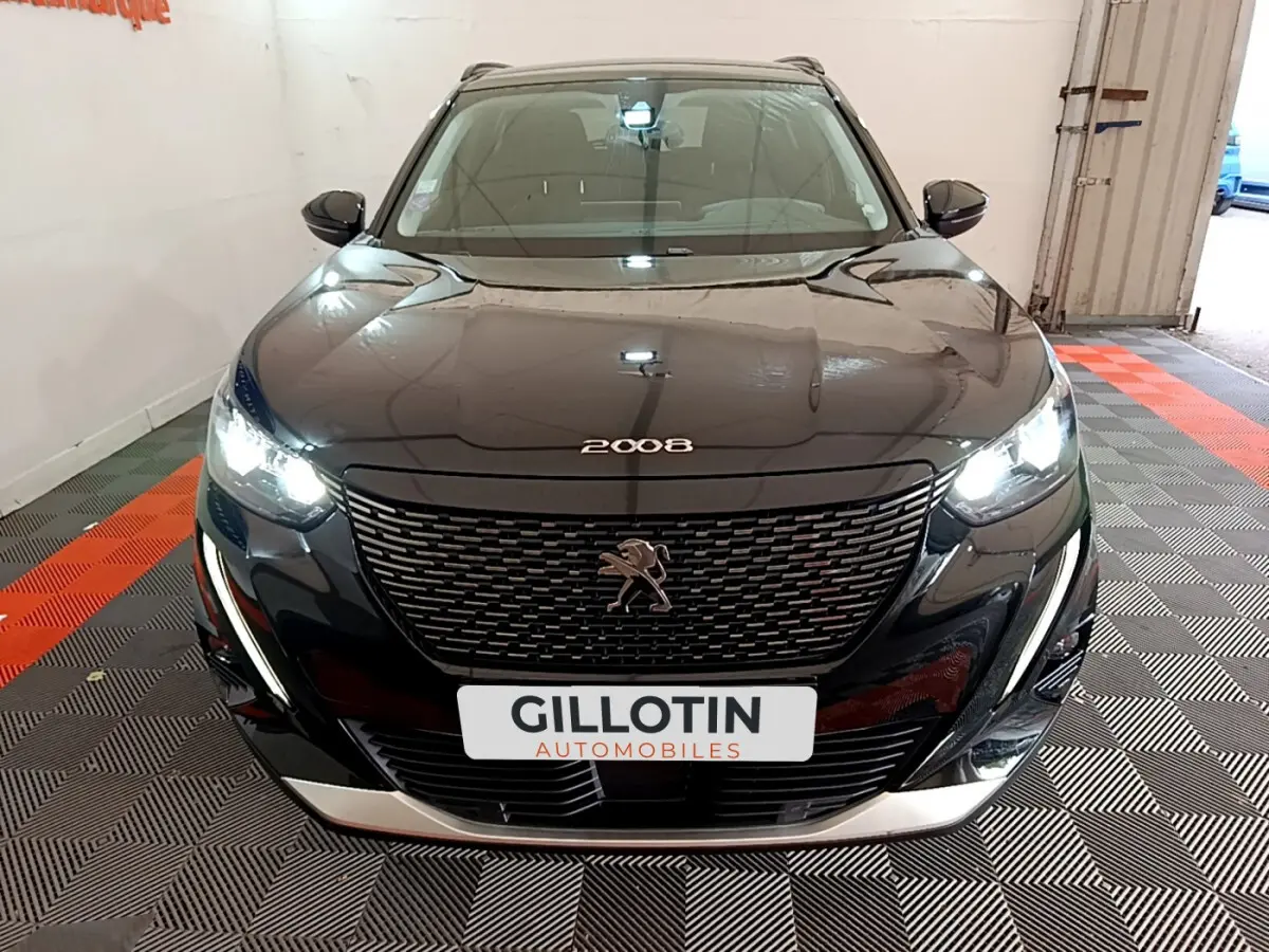 Peugeot 2008 noir vue de face en intérieur, phares LED allumés et calandre distinctive avec logo lion.