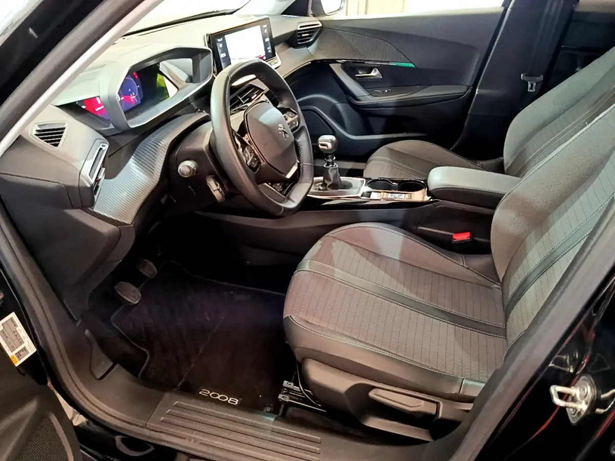 Intérieur avant droit du Peugeot 2008 noir 2021, volant cuir, écran tactile 10 pouces et boîte manuelle visible.