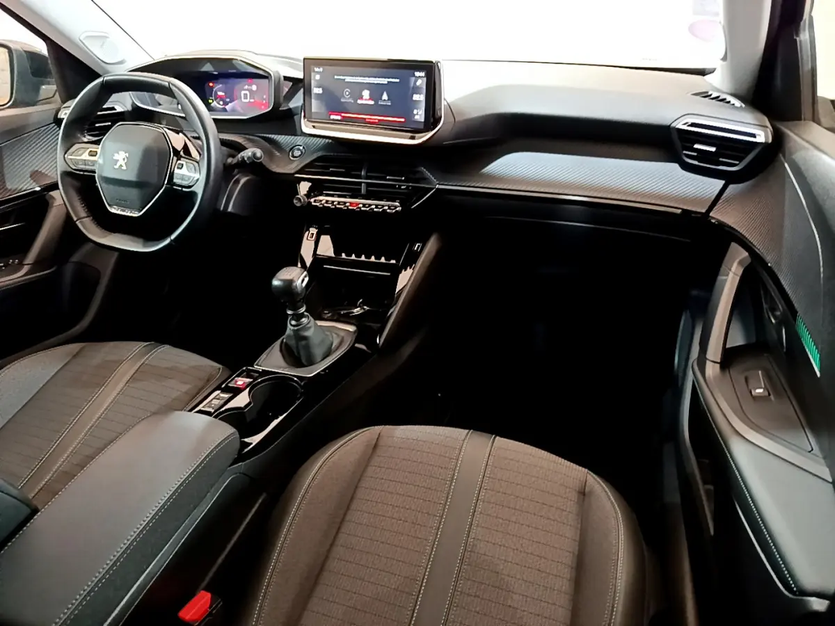 Intérieur noir de la Peugeot 2008 PureTech 130, vue de face montrant volant cuir, écran tactile et levier de vitesse manuel.
