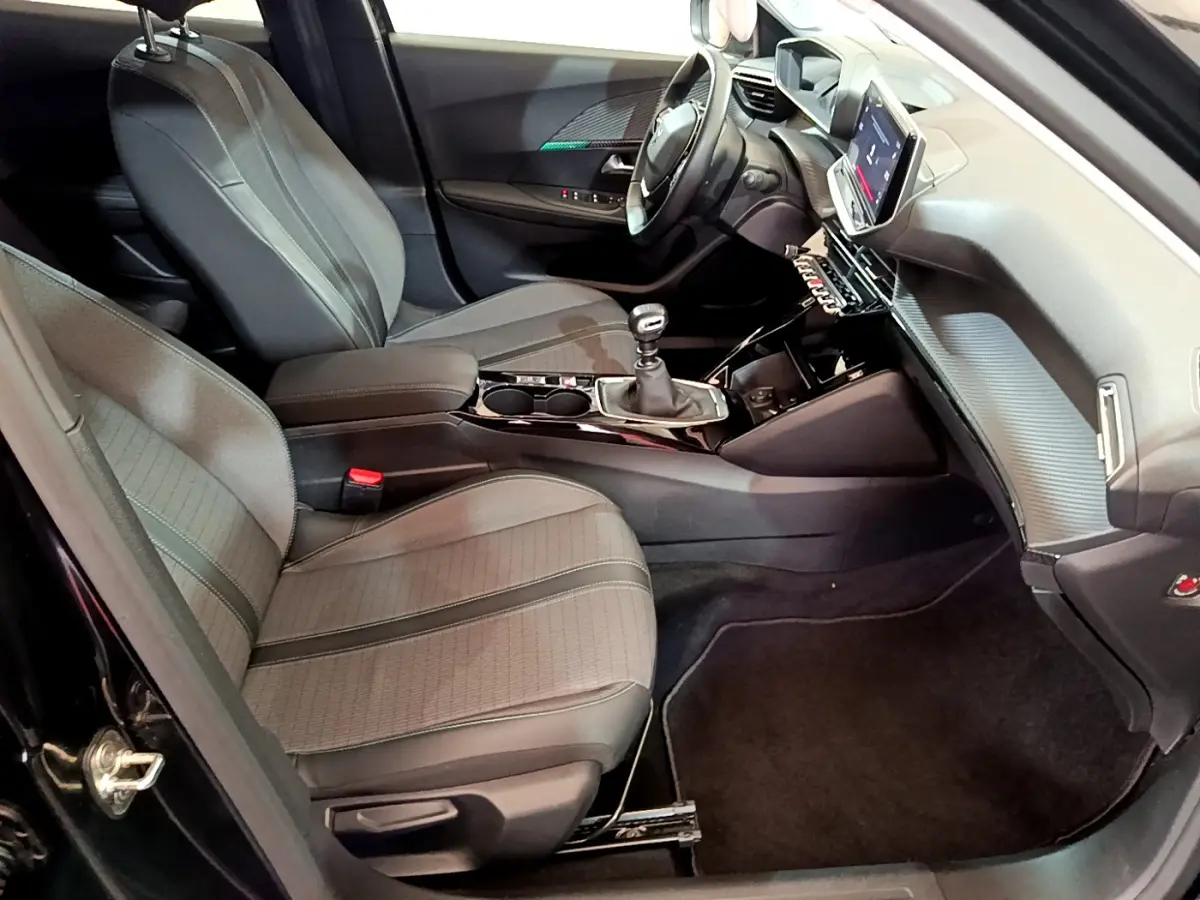 Intérieur de la Peugeot 2008 noir, vue côté conducteur, avec tableau de bord moderne et écran tactile central.