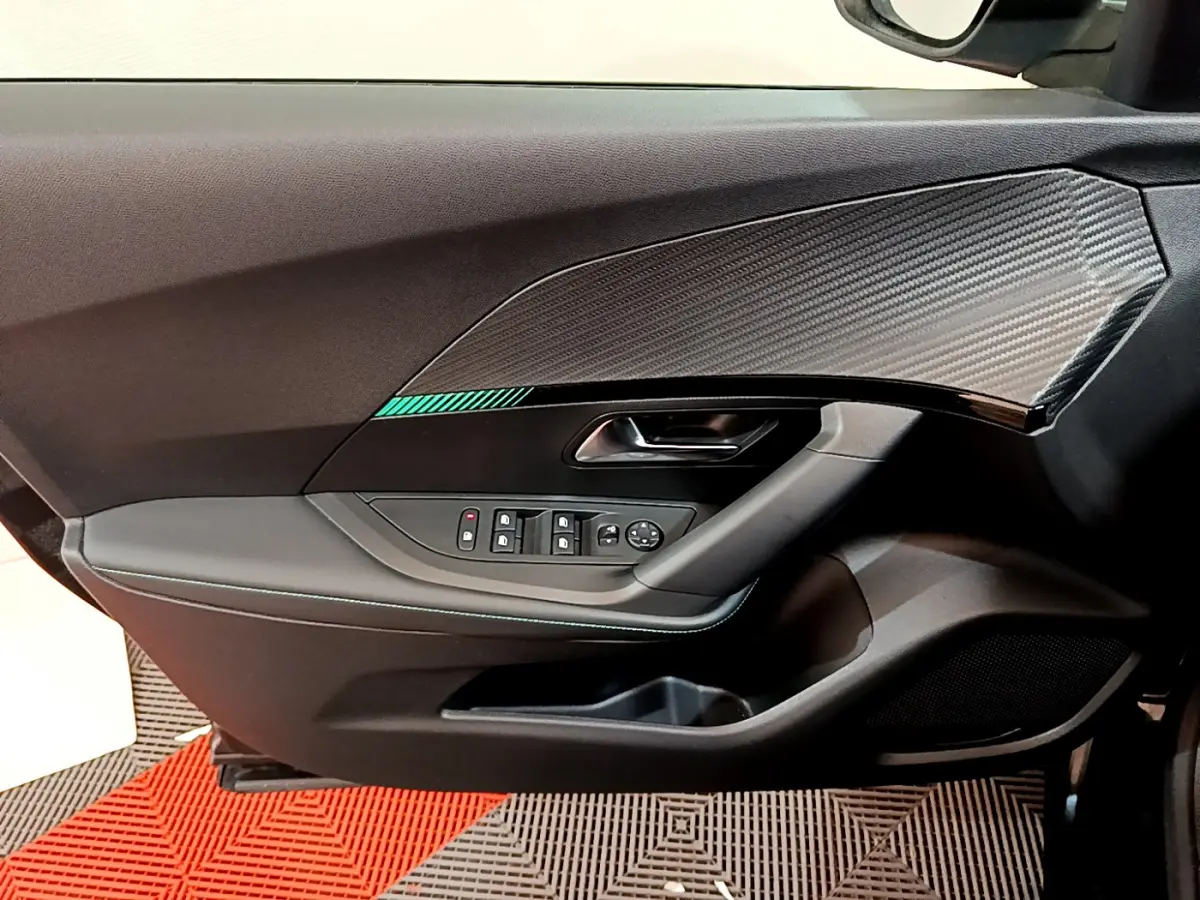 Vue rapprochée de la porte côté gauche du Peugeot 2008 noir, avec insert décoratif effet carbone et commandes électriques.
