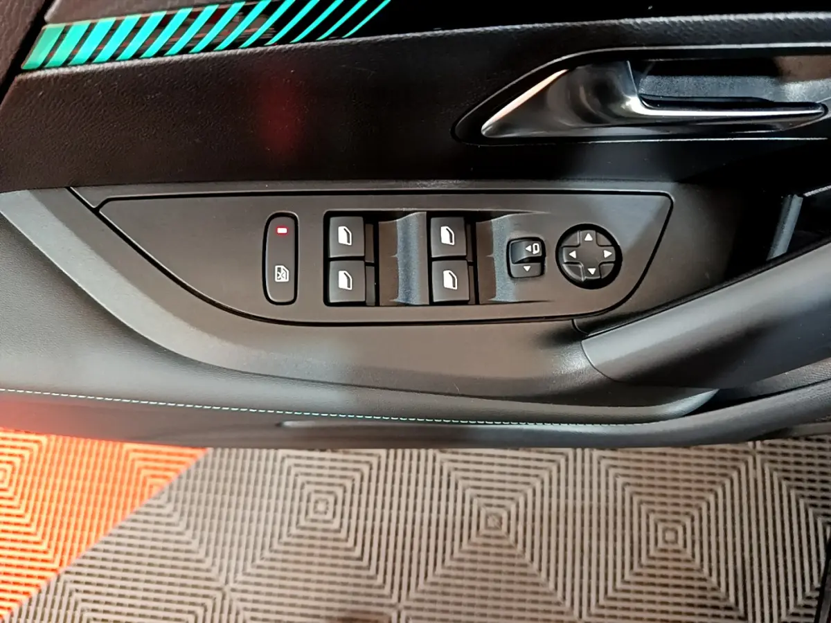 Gros plan sur la commande des vitres électriques côté conducteur du Peugeot 2008 noir, avec poignée de porte métallique.