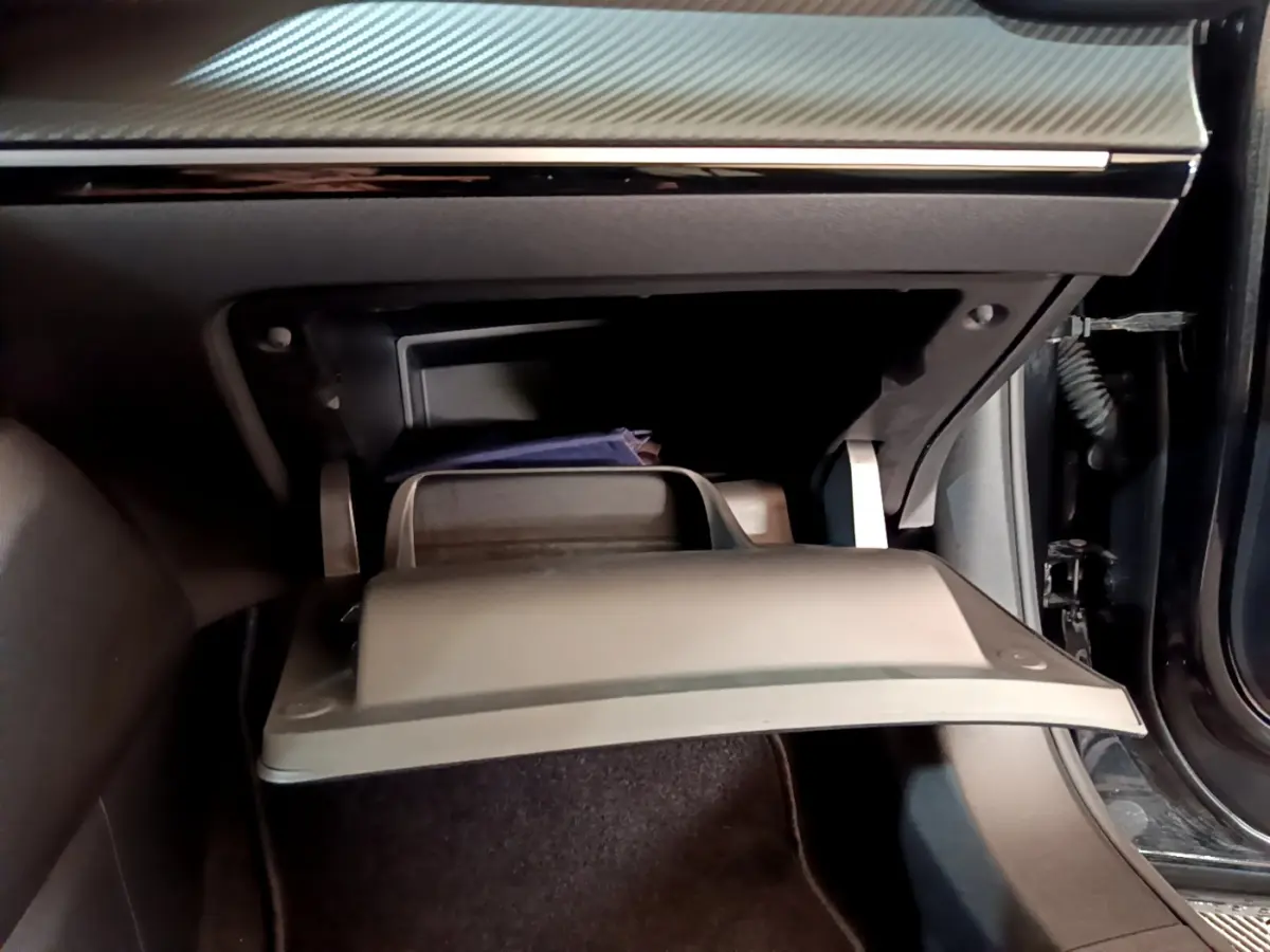 Gros plan sur la boîte à gants ouverte côté passager du Peugeot 2008 noir, montrant un rangement intérieur.