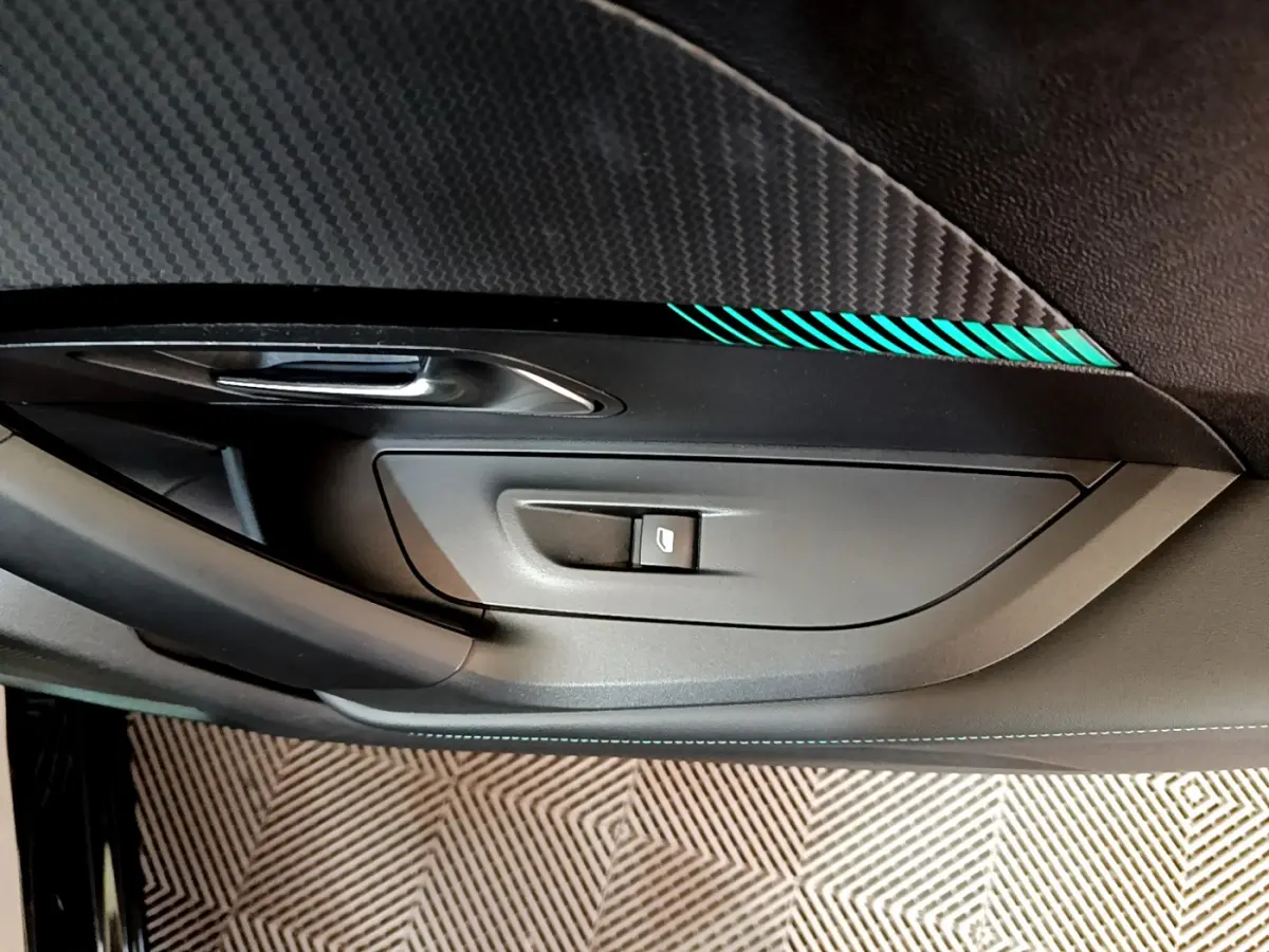 Détail de la porte côté gauche intérieure noire avec bouton de lève-vitre et insert décoratif bleu sur Peugeot 2008 2021.