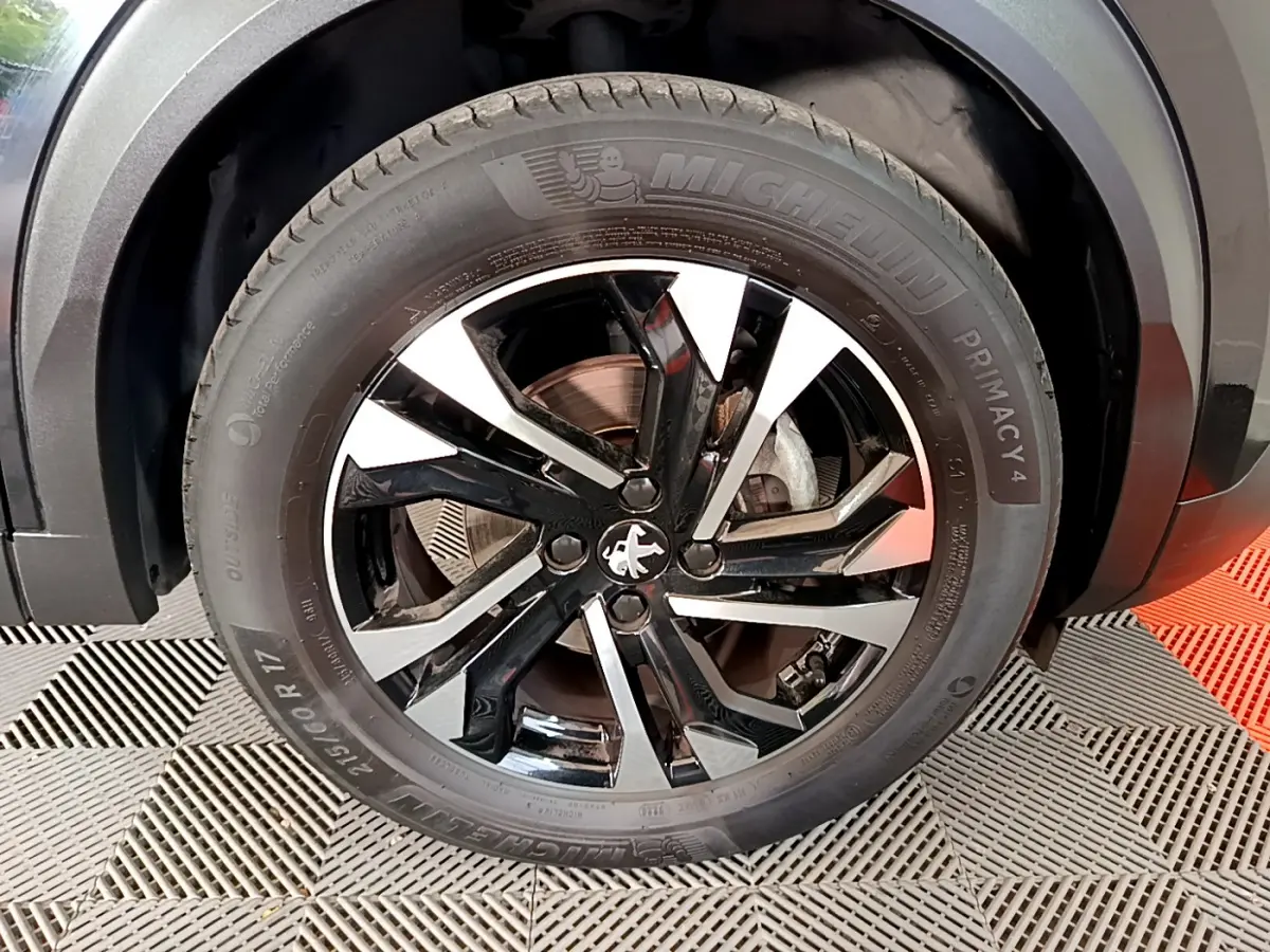 Gros plan sur la jante noire et argentée d'une Peugeot 2008 PureTech 130, avec pneu Michelin Primacy 4 visible.