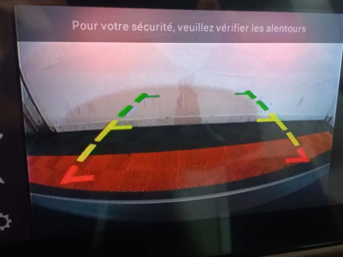 Vue de la caméra de recul de la Citroën C3 hybride gris foncé, avec lignes de guidage colorées et message de sécurité.