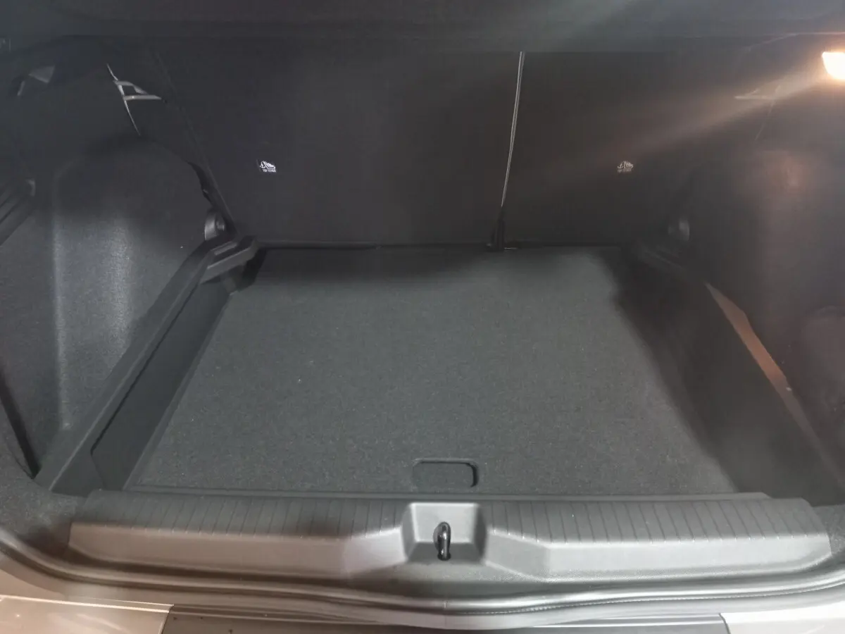 Vue intérieure du coffre spacieux et vide de la Citroën C3 hybride gris foncé, avec banquette arrière rabattue.