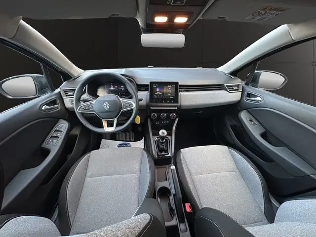 Vue intérieure avant de la Renault Clio V 1.5 DCI noire, avec tableau de bord numérique et sellerie textile grise à motif 3D.