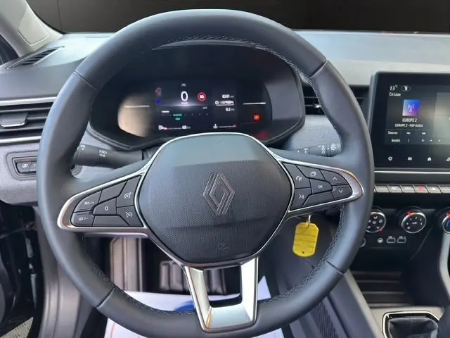 Vue rapprochée du volant noir de la Renault Clio V avec tableau de bord numérique et écran multimédia à droite.