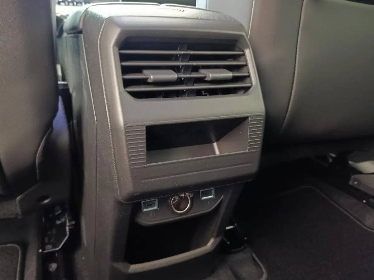 Détail de la console arrière noire avec bouches d’aération et prises USB dans une Citroën C5 Hybride verte.