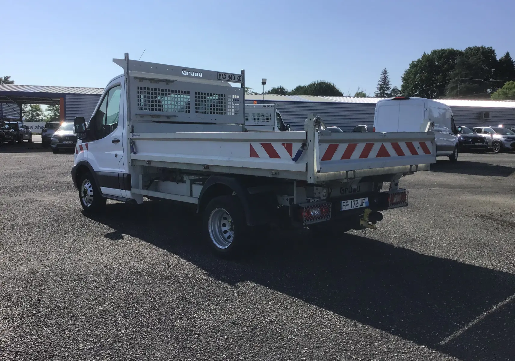 Ford Transit Chassis Cabine blanc vu en 3/4 arrière droit avec benne et marquages rouges réfléchissants.