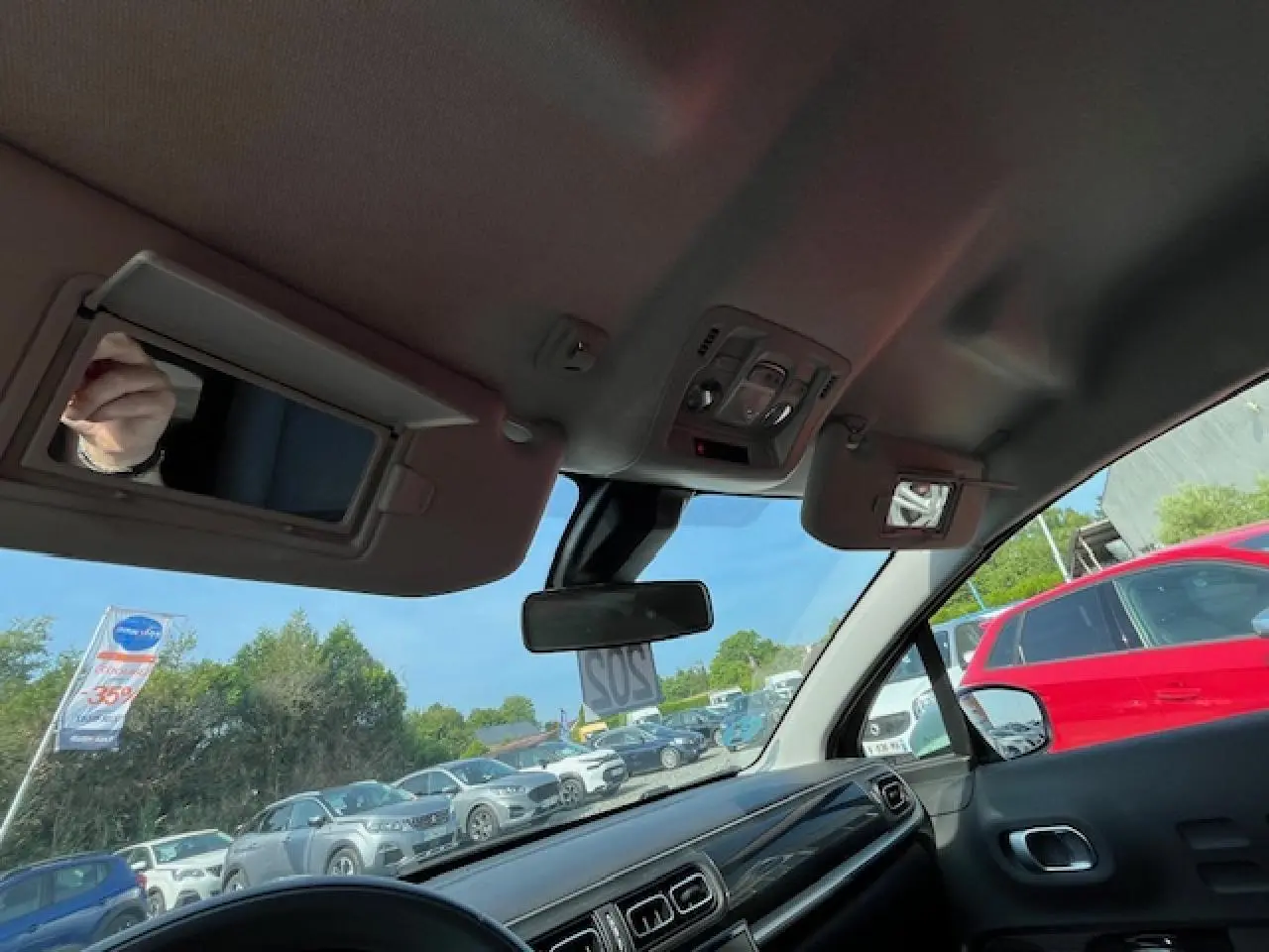 Vue intérieure avant de la Citroën C3 noire 2023, montrant tableau de bord et pare-soleils avec miroirs ouverts.